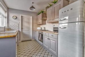 une cuisine avec des armoires blanches et un réfrigérateur dans l'établissement Ebenezer House, à Newbiggin-by-the-Sea