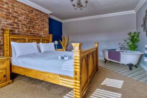 1 dormitorio con cama de madera y bañera en Ebenezer House en Newbiggin-by-the-Sea