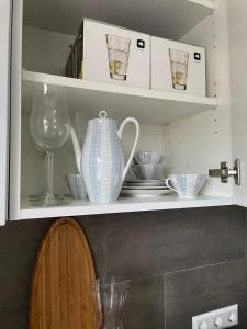 uma prateleira de cozinha com pratos e um vaso sobre ela em Gemütliches Appartement mit eigener Terrasse em Lindau-Bodolz