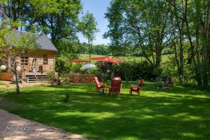 a yard with chairs and an umbrella and a cabin at Haute Dône in Luzy