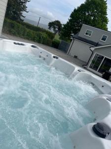 une baignoire remplie d'eau devant une maison dans l'établissement 4 Bed cottage with Hot tub, à Bannockburn