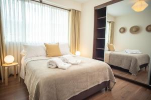 コチャバンバにあるApartamenteo White Lama - Skyのベッドルーム1室(ベッド2台、ベッド上にタオル付)