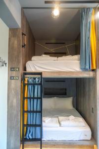 2 Etagenbetten in einem kleinen Zimmer mit einer Leiter in der Unterkunft 澎湖 玩聚背包民宿 in Huxi