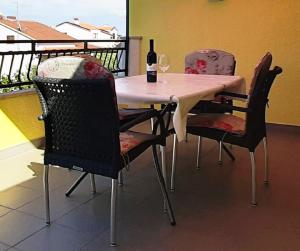 a table with chairs and a bottle of wine on a balcony at PARADISE Beach Apartments in Rovinj