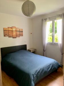 Un dormitorio con una cama azul y una ventana en Le clos rozan, en Sainte-Eulalie-en-Born