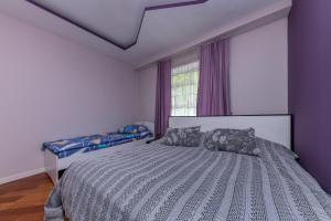 a bedroom with a bed with purple walls and a window at Wanderlust boutique hostel in Almaty