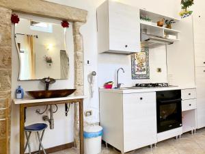 a white kitchen with a sink and a counter at Corte Merlata Apartments in Galatone