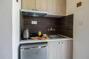 uma pequena cozinha com um lavatório e um fogão em Kolevri Studios em Laganas