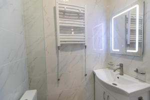 Baño blanco con lavabo y espejo en TAMO Rooms en Tiflis