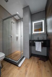 uma casa de banho com uma cabina de duche em vidro e um WC. em Hotel Boutique Britanico em Gramado