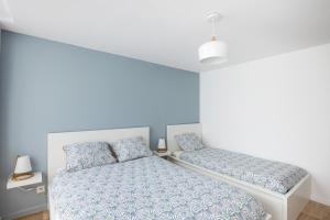 a bedroom with two beds with blue walls at Le Maetica - 5 min de Disneyland Paris in Coupvray