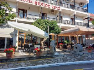 un ristorante con tavoli e sedie di fronte a un edificio di Xenios Zeus a Ouranoupoli