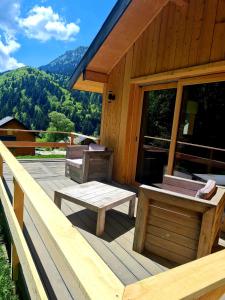 a porch of a cabin with a bench and a table at Le Chalet Du Blanc Spa yoga in Aillon-le-Jeune
