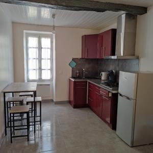 a kitchen with red cabinets and a white refrigerator at Patio en Périgord in Lalinde