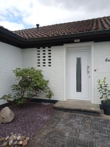 uma casa branca com uma porta branca e uma pedra em Sommerheide em Bad Bevensen