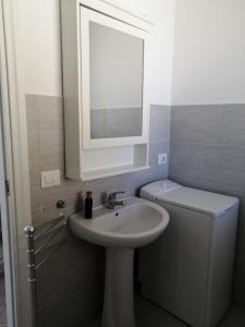 a bathroom with a sink and a mirror and a toilet at CM HOUSE MARZAMEMI in Marzamemi