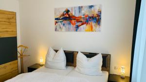 - une chambre dotée d'un lit avec des oreillers blancs et un tableau dans l'établissement Ferienwohnung Mühlwang, à Gmunden