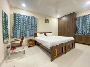 a bedroom with a bed and a chair and blue curtains at VOILA AT NEST in Hyderabad