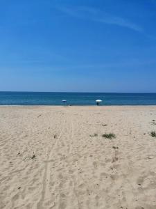 a sandy beach with an umbrella and the ocean at Appartamento Salvia in centro in Ascea