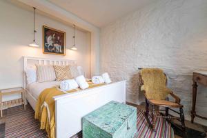 a bedroom with a white bed and a chair at Secret Cottage in St Ives
