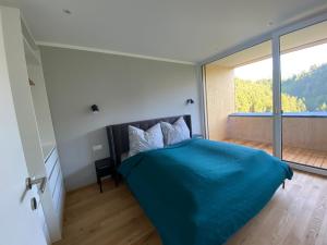 ein Schlafzimmer mit einem blauen Bett und einem großen Fenster in der Unterkunft Wohnung Staufenblick und Wohnung Firstblick in Dornbirn