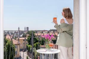 una mujer parada en un balcón sosteniendo una copa de vino en ReGo Apartments, en Bérgamo