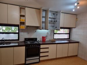 uma cozinha com armários brancos e um forno com placa de fogão em Departamento Mendoza em Mendoza