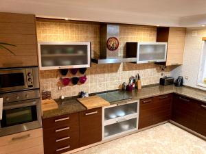 a kitchen with wooden cabinets and stainless steel appliances at A Family house in Santa Cruz, Torres Vedras in Silveira +15 photos
