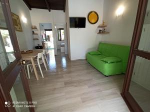 a living room with a green couch and a table at Casa Perla Rei - 50 meters from the beach in Costa Rei
