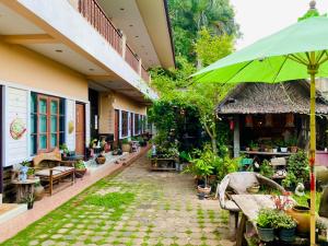 a courtyard of a building with a green umbrella at Thai Guesthouse in Kanchanaburi