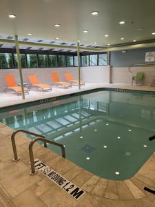uma piscina com cadeiras laranja num edifício em Holiday Inn Express & Suites - Dahlonega - University Area, an IHG Hotel em Dahlonega