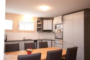 a kitchen with a wooden table and a kitchen with white cabinets at Alpbachstrasse 4, Meiringen in Meiringen