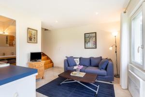 een woonkamer met een blauwe bank en een tafel bij Le Cottage Normand in Annebault