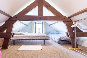 een zolderkamer met een bed en een raam bij Le Cottage Normand in Annebault