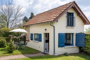 een klein wit huis met blauwe ramen en een paraplu bij Le Cottage Normand in Annebault