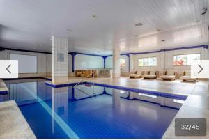 a large swimming pool with chairs and a table at Apartamento em Resort Olímpia in Olímpia