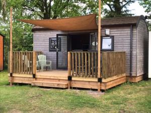 a small house with a deck with a tv on it at Tiny House de Wood Lodge in Ootmarsum