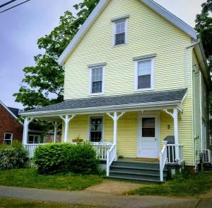 a yellow house with a white porch and stairs at Pink Flamingo in Wolfville