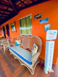 wiklinowy fotel siedzący w pokoju z pomarańczową ścianą w obiekcie Casa Da Didda w mieście Fernando de Noronha
