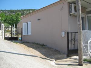a white building with a fence next to a street at George house in Theológos
