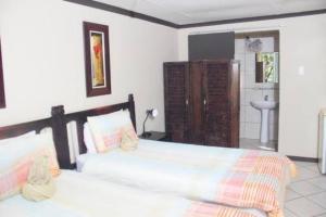 a bedroom with two beds and a bathroom at Petra guest lodge in Edenvale