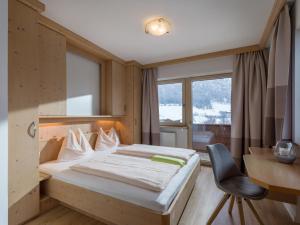 een slaapkamer met een bed, een bureau en een stoel bij Aparthotel Brandauerhof in Walchsee