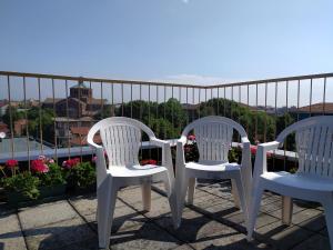 2 sillas blancas en la parte superior de un balcón en La Terrazza su Monza Casa Vacanze, en Monza
