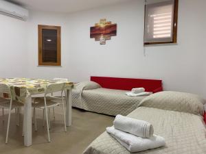 Cette chambre comprend deux lits, une table et des chaises. dans l'établissement A&G Casa Vacanze Naxos-Taormina, à Giardini Naxos
