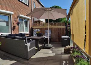 eine Terrasse mit einem Tisch und einem Sonnenschirm in der Unterkunft CasaLuca in Hellevoetsluis