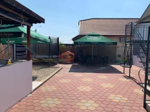 un patio avec des tables et des parasols verts à côté d'un bâtiment dans l'établissement CasaRiana 1, à Eforie Sud