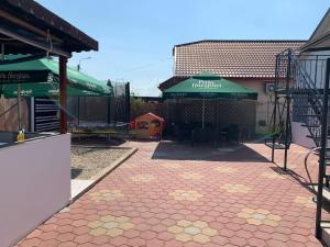 un patio con mesas y sombrillas verdes junto a un edificio en R i A N A 1, en Eforie Sud