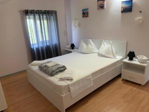 um quarto com uma cama com lençóis brancos e almofadas em CasaRiana 2 em Eforie Sud