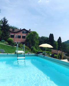 a swimming pool with a chair and an umbrella at Villa Le Vignole in Ameno