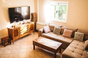 sala de estar con sofá y TV de pantalla plana en Villa Gana, en Buna